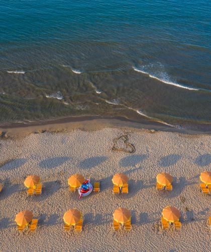 Spiaggia con ombrelloni arancioni e mare calmo.