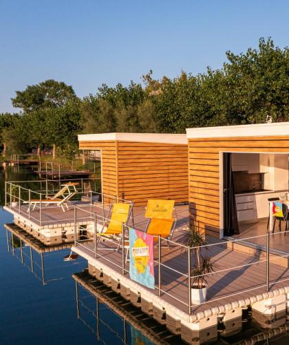 Casa galleggiante moderna con terrazza sul lago, circondata da alberi.