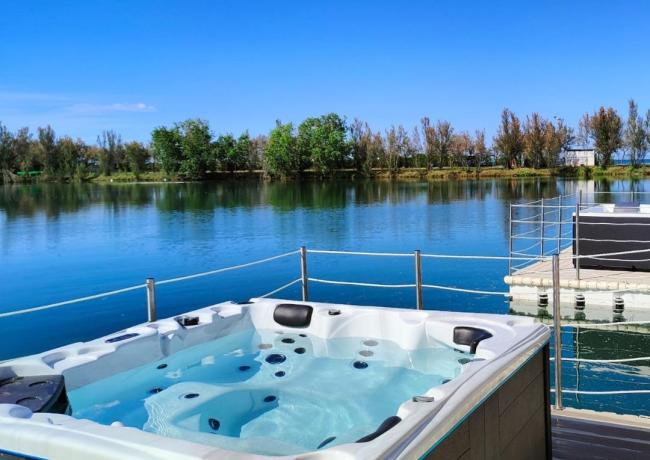 Vasca idromassaggio con vista lago e cielo blu.