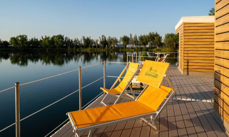 Lettini su terrazza affacciata su un lago tranquillo al tramonto.