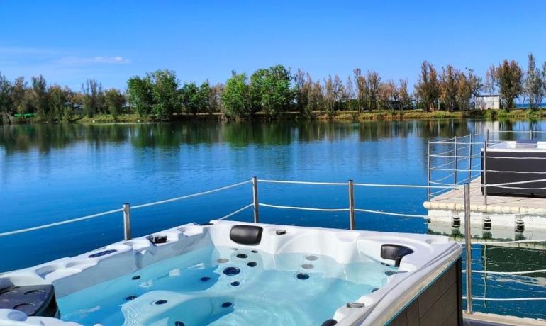 Vasca idromassaggio con vista lago e cielo blu.